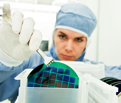 Foto einer Wissenschaftlerin bei der Verarbeitung eines Silizium-Wafers im Reinraum